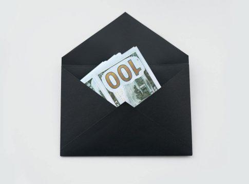 Stack of cash inside an open physical envelope labeled 