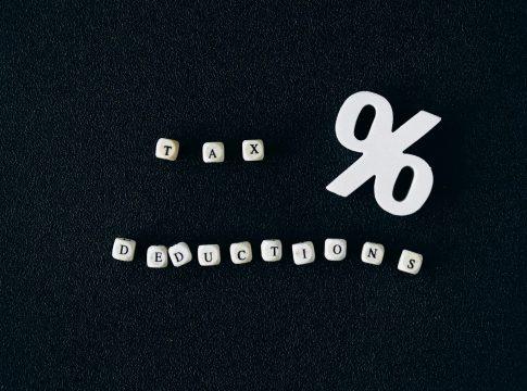 Magnifying glass over a stack of coins and tax forms.