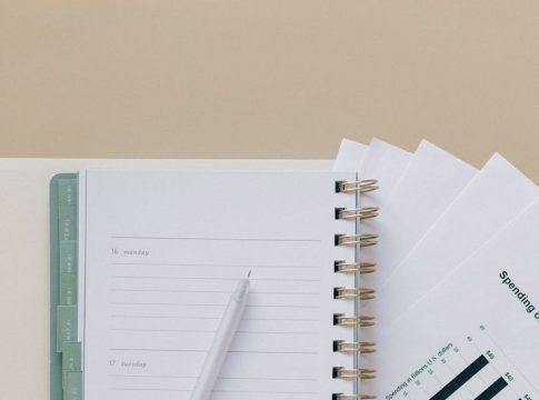 Woman reviewing financial documents with a planner, assessing the cost.