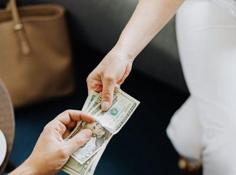 Woman smiling, holding a stack of cash, illustrating debt payoff success.