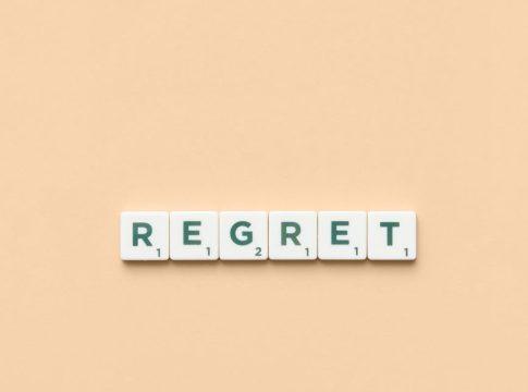 Person looking thoughtfully at a stack of coins and bills.
