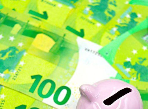 Woman looking stressed while looking at bills and a piggy bank.